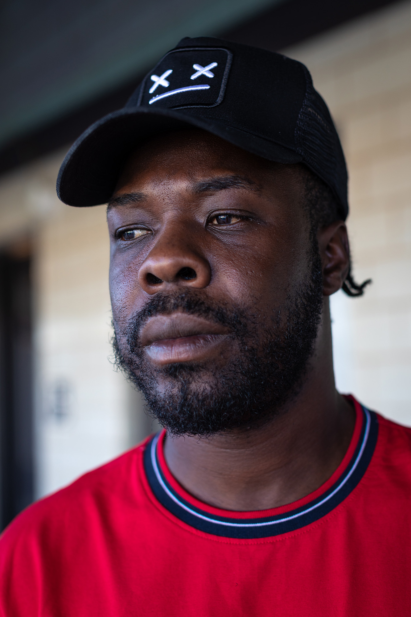 Portrait of a man in a red shirt and black baseball hat.