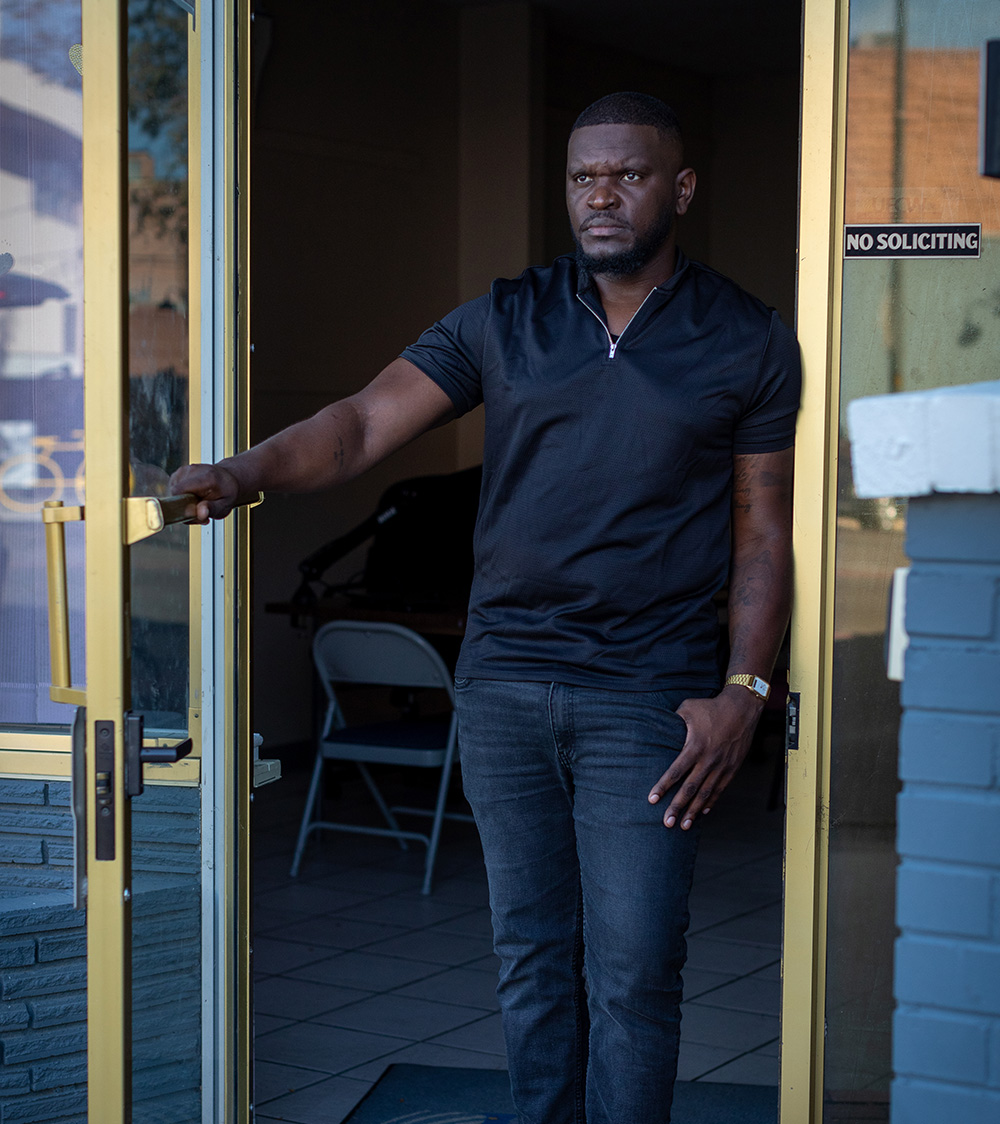 Man standing in a doorway, holding the door open.
