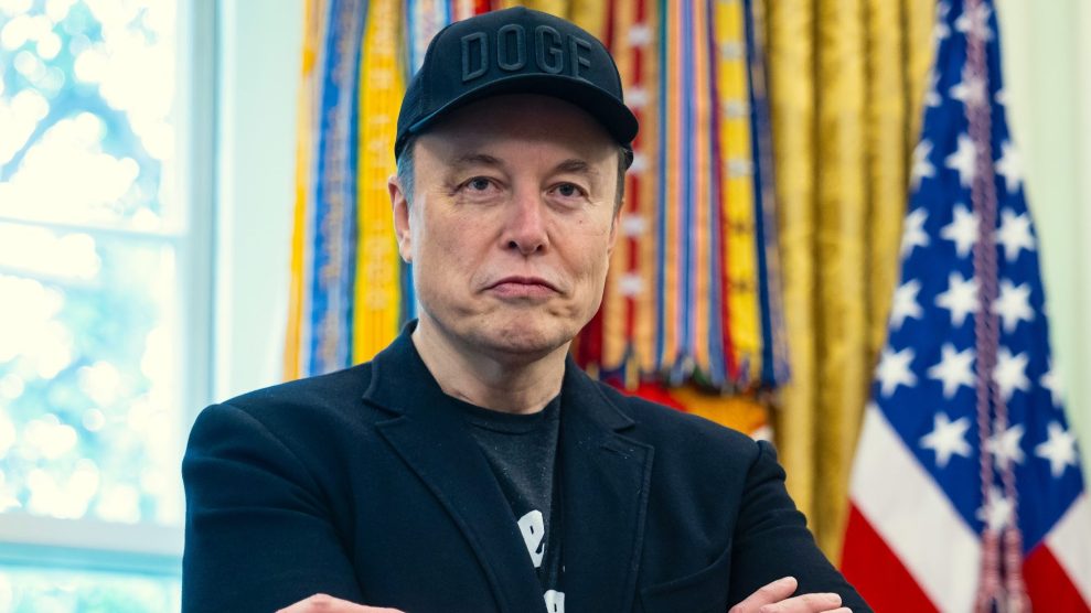 Picture of Musk in the Oval Office wearing a black DOGE baseball cap.